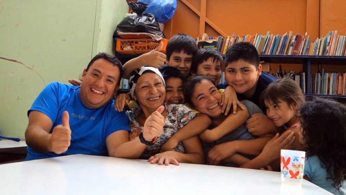 Gruppe von lächelnden Kindern und Erwachsenen in einem Raum, fröhliche Atmosphäre.