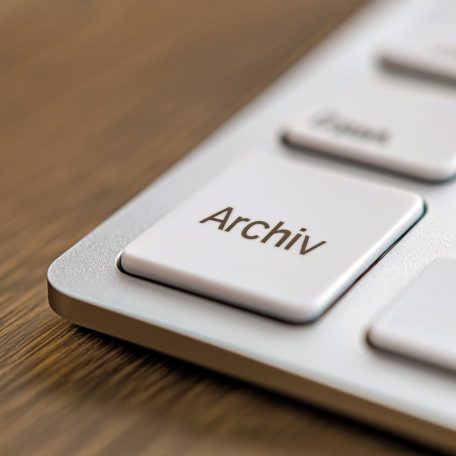 Tastatur mit einer Taste mit der Beschriftung "Archiv" auf einem Holzuntergrund.