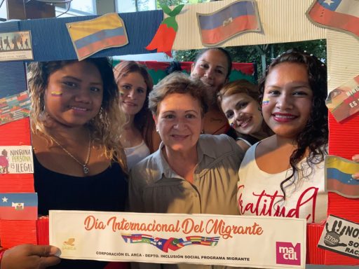 Gruppenselfie von Frauen mit venezolanischen Flaggen und einem Textrahmen zum Tag der Migration.