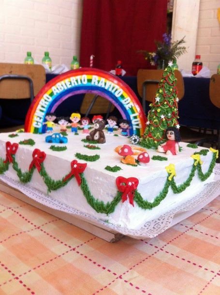 Bunter Festtagskuchen mit Figuren, Weihnachtsbaum und buntem Regenbogen.