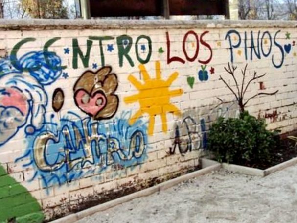 Bunte Wandmalerei mit dem Schriftzug "Centro Los Pinos" und abstrakten Motiven.