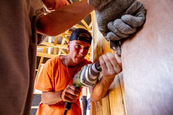 Handwerker mit Bohrer, der präzise an einer Wand arbeitet.