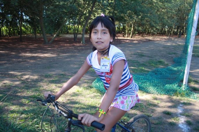 Ein Mädchen fährt auf einem Fahrrad in einem parkähnlichen Gelände.